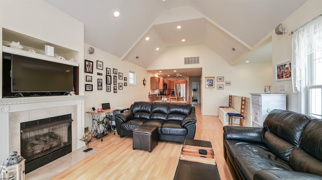 living room with visible vents, wood finished floors, high vaulted ceiling, recessed lighting, and a tile fireplace
