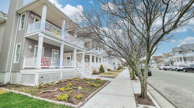 view of property exterior featuring covered porch, a residential view, and a balcony