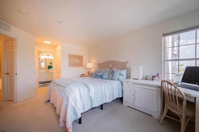 bedroom featuring visible vents, ensuite bath, and light colored carpet