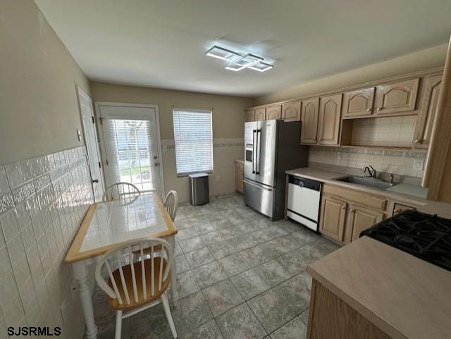 kitchen with light brown cabinets, light countertops, stainless steel fridge with ice dispenser, a sink, and dishwasher