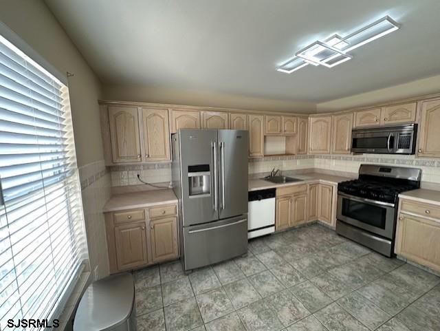 kitchen with light countertops, appliances with stainless steel finishes, a sink, and light brown cabinets
