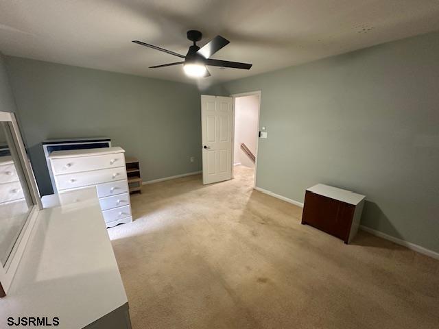 unfurnished bedroom featuring baseboards, ceiling fan, and light carpet