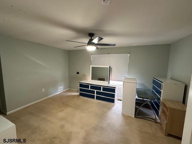 interior space with visible vents, baseboards, ceiling fan, and light carpet