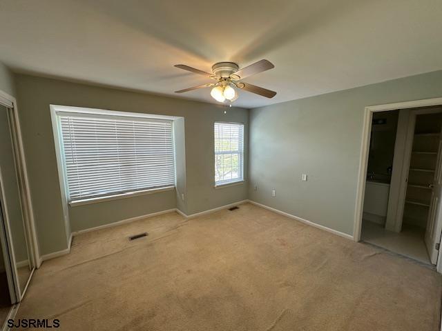 unfurnished bedroom featuring baseboards, light colored carpet, and ceiling fan