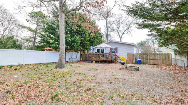 rear view of property with a fenced backyard, an outdoor fire pit, and a wooden deck
