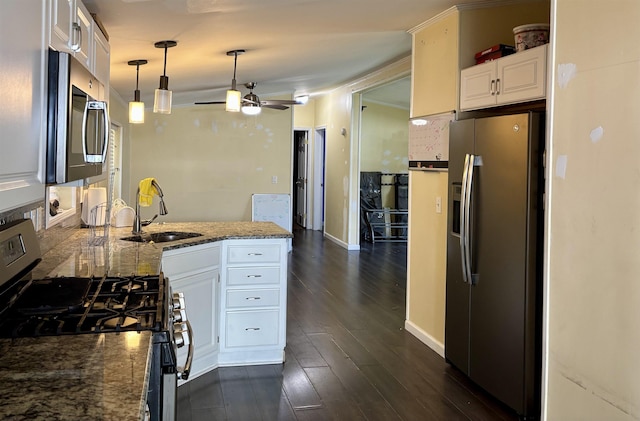 kitchen featuring a ceiling fan, appliances with stainless steel finishes, a sink, white cabinets, and a peninsula