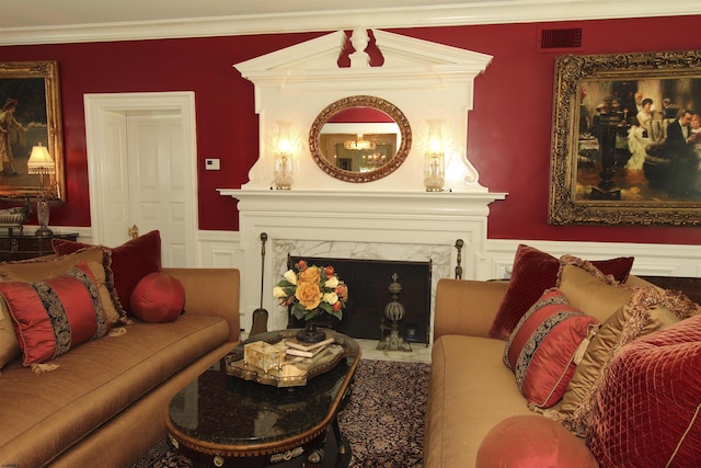 living room featuring visible vents, crown molding, a high end fireplace, wainscoting, and a decorative wall
