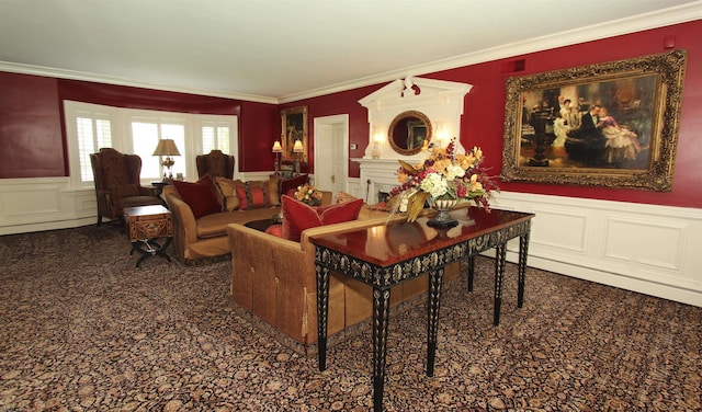 living area featuring a fireplace, carpet floors, a decorative wall, a wainscoted wall, and ornamental molding