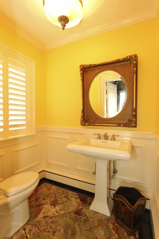 half bath with crown molding, toilet, wainscoting, and a decorative wall