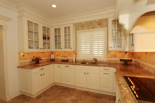 kitchen featuring backsplash, a sink, black electric stovetop, dark stone counters, and white cabinetry