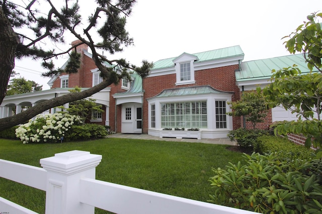 back of house with brick siding, metal roof, a yard, and a standing seam roof