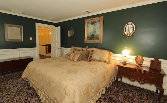 carpeted bedroom featuring a wainscoted wall, ornamental molding, and visible vents