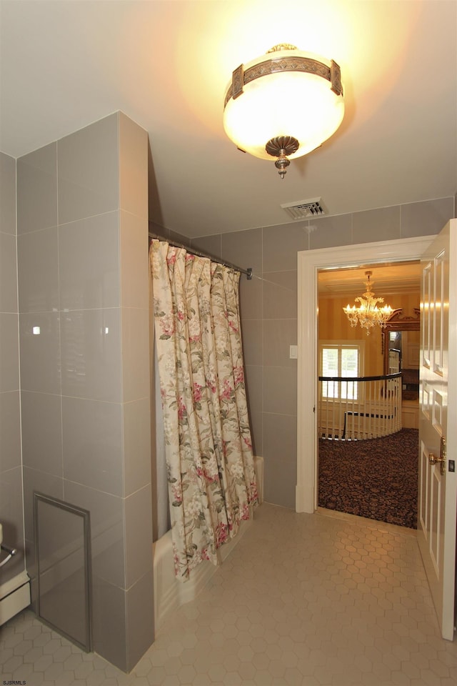 full bath featuring visible vents, tile walls, tile patterned flooring, baseboard heating, and a chandelier