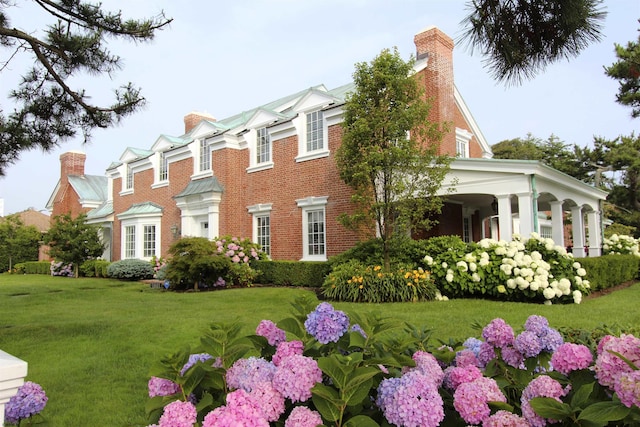 view of home's exterior featuring a lawn, brick siding, and a chimney