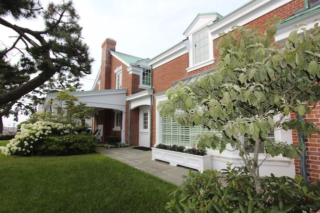 view of side of home featuring a lawn, a chimney, and brick siding