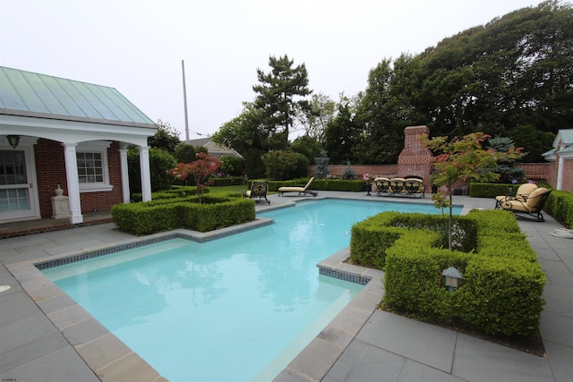 pool with a patio and a fireplace