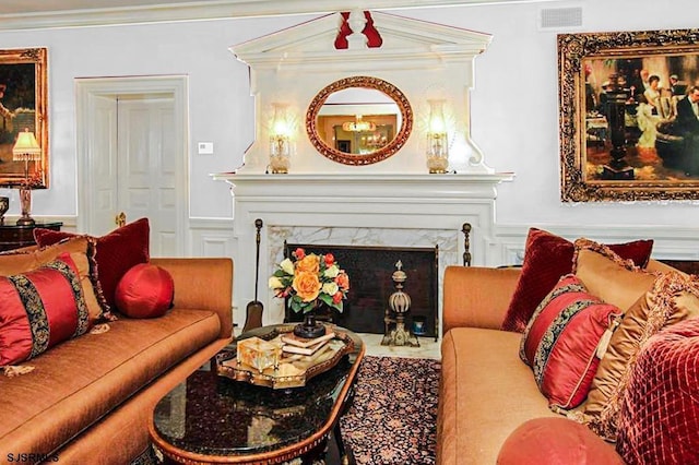 living area with a decorative wall, crown molding, visible vents, and a fireplace