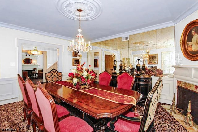 dining space featuring an inviting chandelier, ornamental molding, a decorative wall, and a wainscoted wall