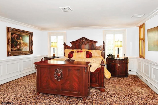 bedroom featuring visible vents, ornamental molding, a decorative wall, and multiple windows