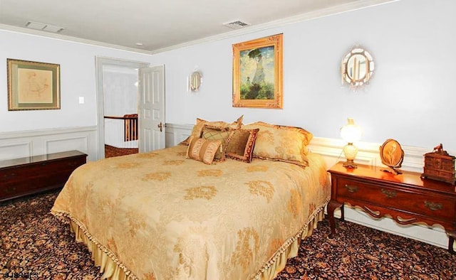 bedroom with carpet flooring, crown molding, visible vents, and wainscoting