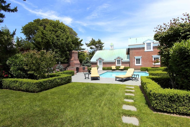 outdoor pool featuring a yard, a patio, and a fireplace