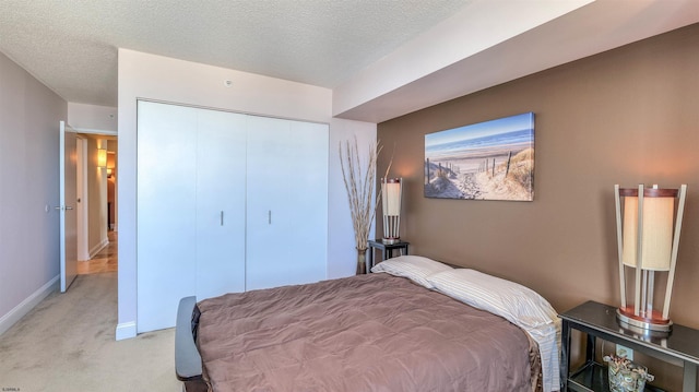 bedroom with light colored carpet, a textured ceiling, baseboards, and a closet