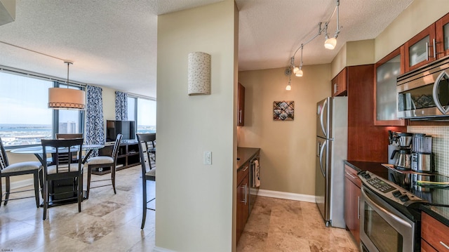 kitchen with dark countertops, a textured ceiling, stainless steel appliances, baseboards, and glass insert cabinets
