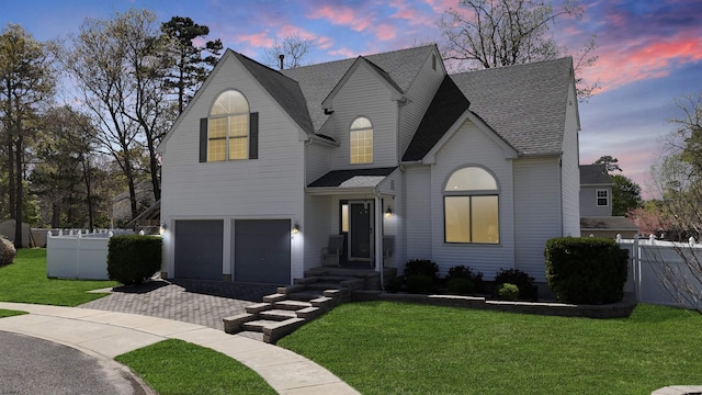 french country home featuring a yard, decorative driveway, an attached garage, and fence