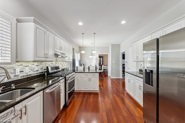 kitchen with white cabinets, appliances with stainless steel finishes, a sink, a peninsula, and under cabinet range hood