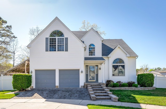 view of front of house with a front yard, roof with shingles, decorative driveway, fence, and an attached garage