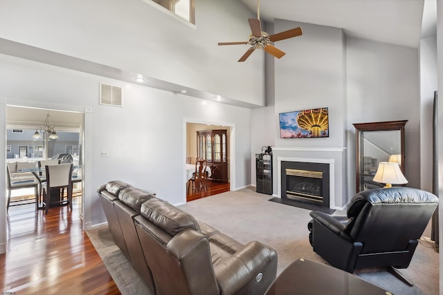 living area with ceiling fan, high vaulted ceiling, baseboards, a fireplace with flush hearth, and visible vents
