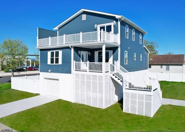 back of house featuring a lawn, an attached garage, a balcony, and stairs