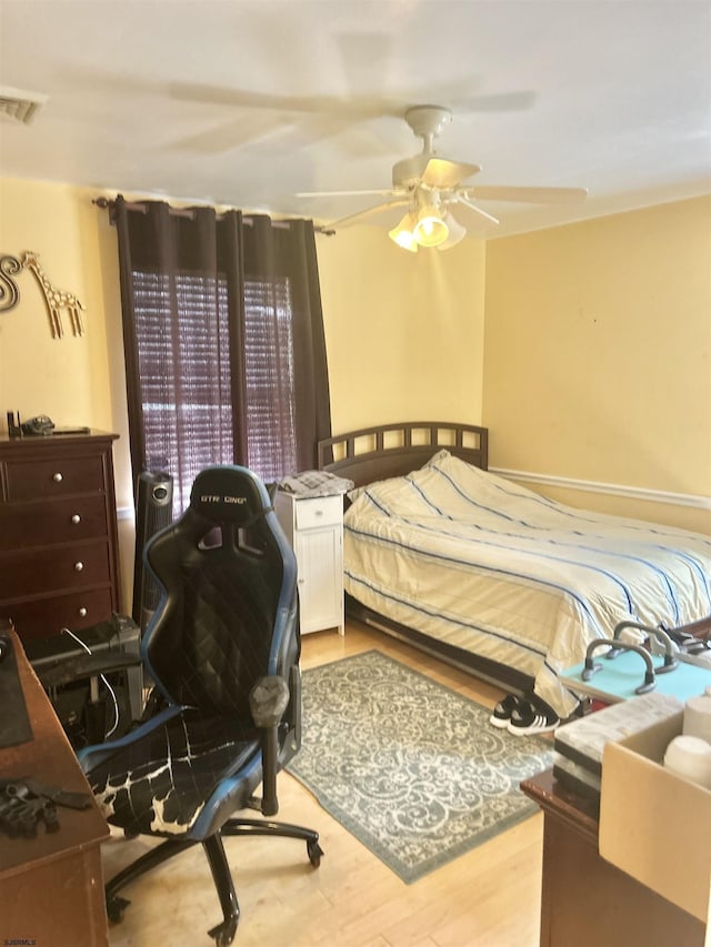bedroom with a ceiling fan, wood finished floors, and visible vents