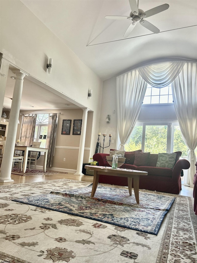 living room with ornate columns, high vaulted ceiling, a ceiling fan, and baseboards