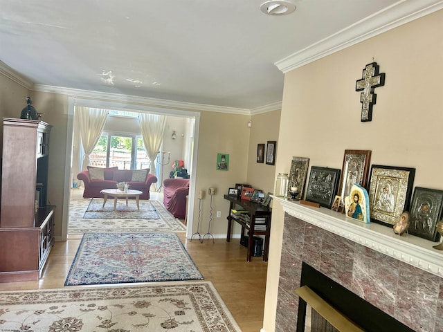living area with crown molding, baseboards, wood finished floors, and a fireplace