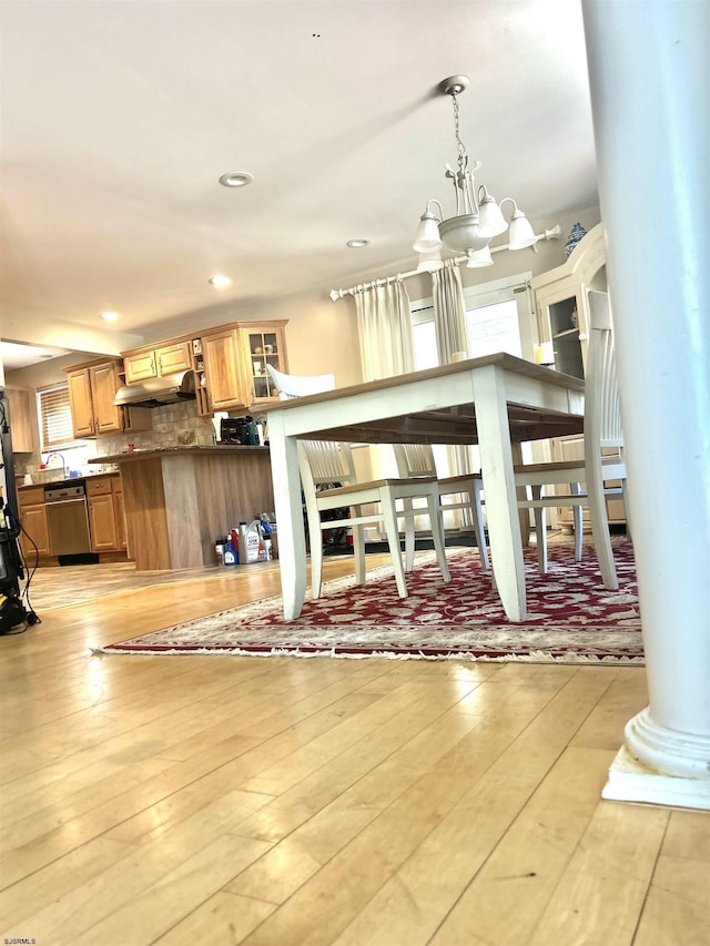 living room featuring ornate columns, a wealth of natural light, light wood finished floors, and a chandelier