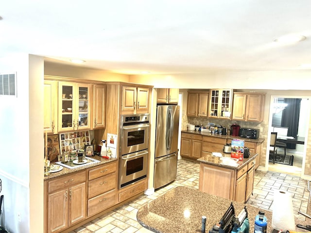kitchen with stainless steel appliances, decorative backsplash, brick floor, and a center island