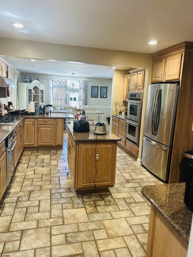 kitchen featuring stainless steel appliances, decorative backsplash, brick floor, and dark stone countertops