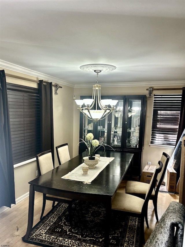 dining room featuring light wood-style floors, ornamental molding, baseboards, and a notable chandelier