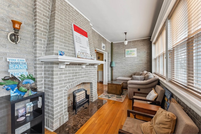 living room with a brick fireplace, ornamental molding, and wood finished floors