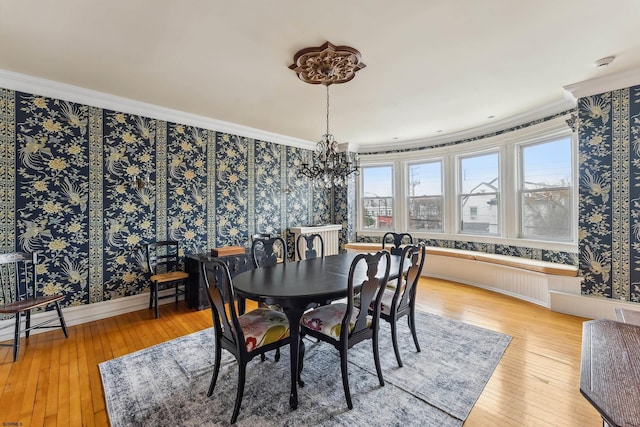 dining room with an inviting chandelier, ornamental molding, wood-type flooring, and wallpapered walls