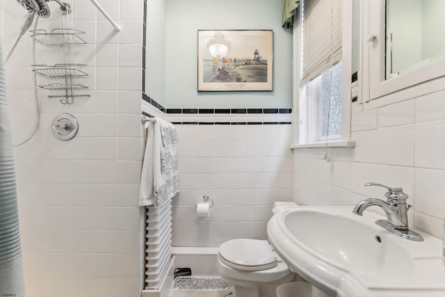 full bath featuring a sink, a tile shower, toilet, and tile walls