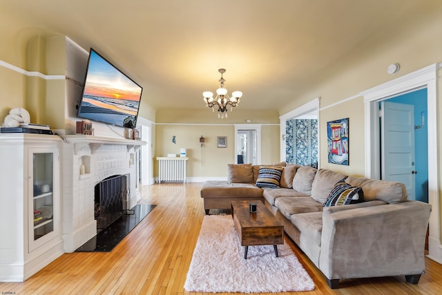 living area featuring baseboards, a fireplace, hardwood / wood-style flooring, and a chandelier
