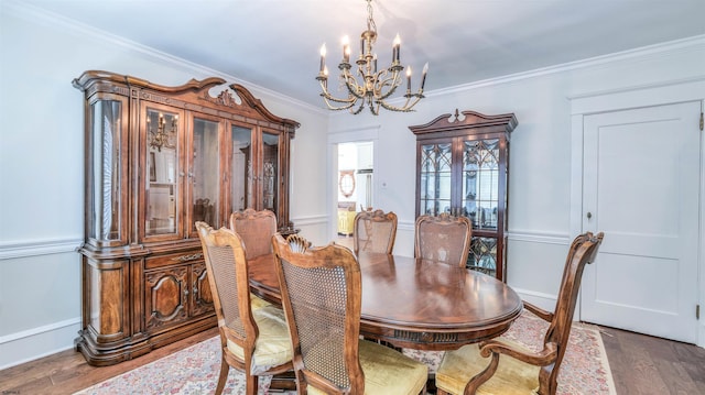 dining space with crown molding, baseboards, a chandelier, and wood finished floors