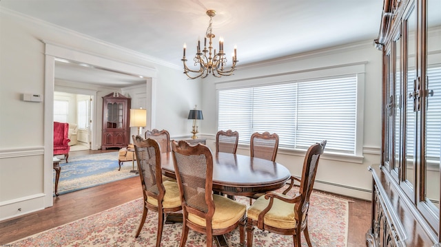 dining area featuring crown molding, a baseboard heating unit, wood finished floors, and a chandelier