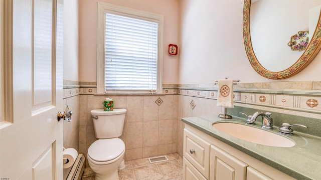 half bath with wainscoting, visible vents, vanity, toilet, and a baseboard heating unit