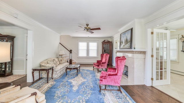 living area featuring a high end fireplace, a ceiling fan, crown molding, and a baseboard heating unit