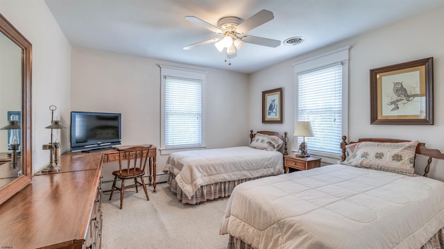 carpeted bedroom with multiple windows, a baseboard heating unit, ceiling fan, and visible vents