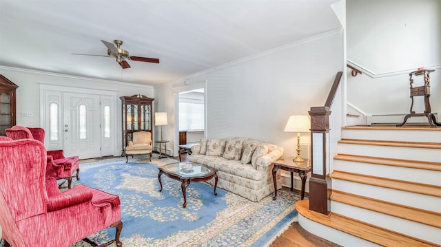 living area featuring stairs, ceiling fan, ornamental molding, and wood finished floors