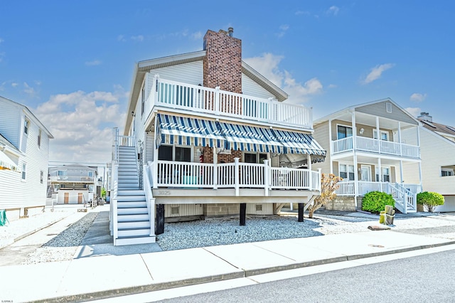 view of front of property featuring stairs, a chimney, and a porch